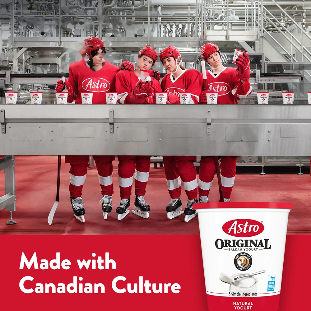 A hockey team examining Astro tubs of yogurt at a factory.