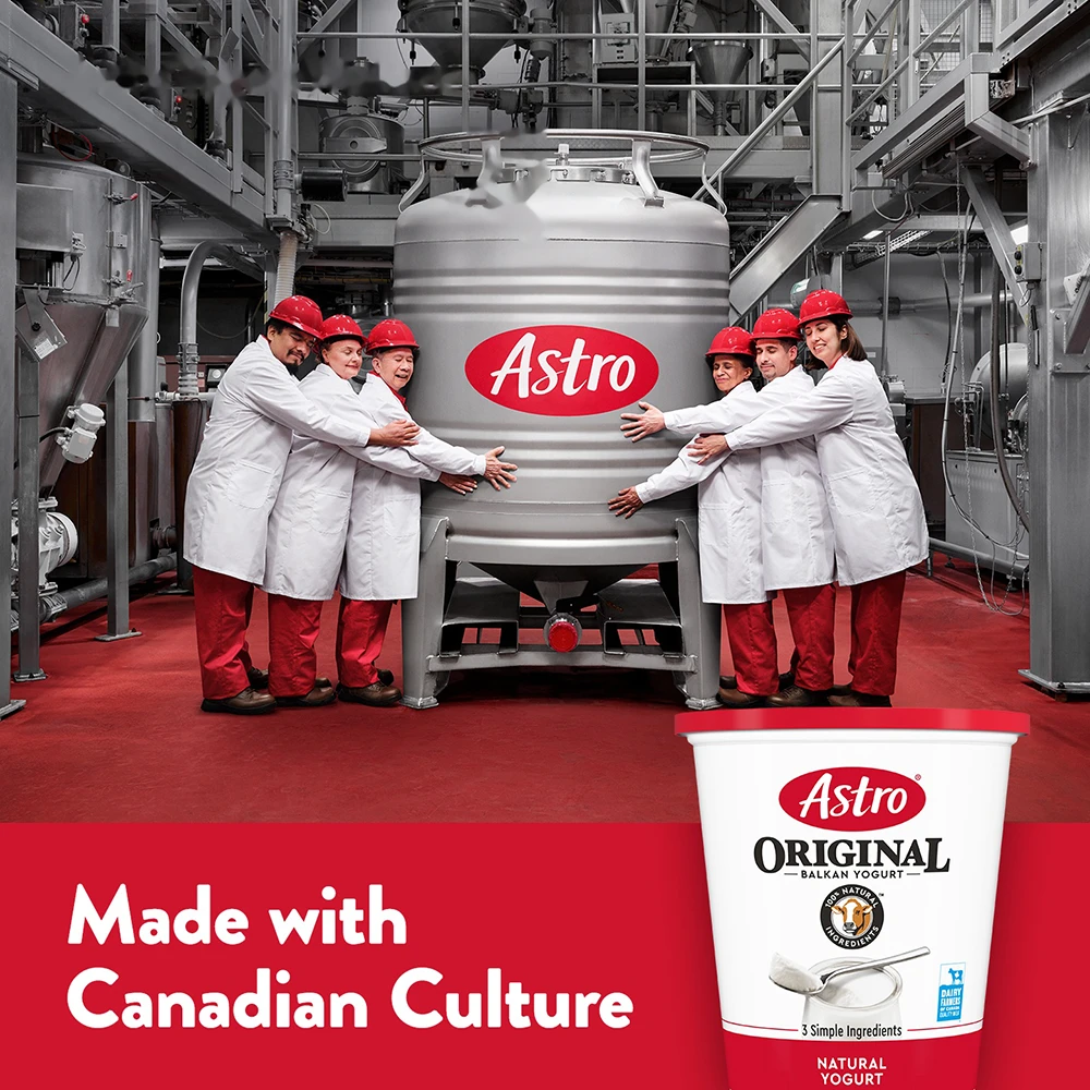 Astro factory staff hugging a vat of yogurt in a factory.